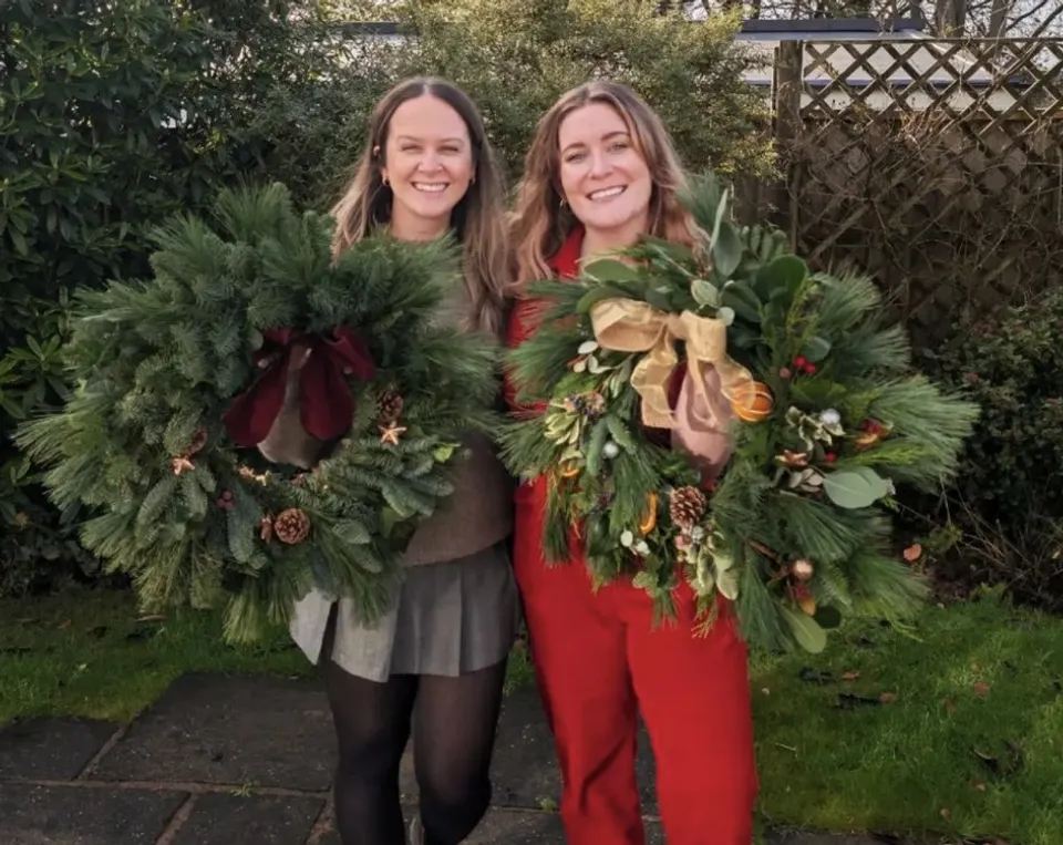 Two friends holding the Christmas wreaths they made at a Fia Florals workshop